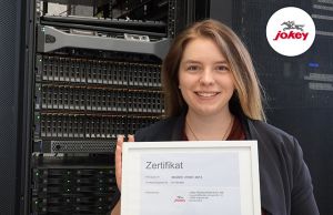 Sidney Engelberth präsentiert das Zertifikat- Jokey baut seine Informationssicherheit kontinuierlich aus und hat das Audit zur Zertifizierung seines Information Security Management Systems (ISMS) nach ISO/IEC 27001:2013 erfolgreich abgeschlossen